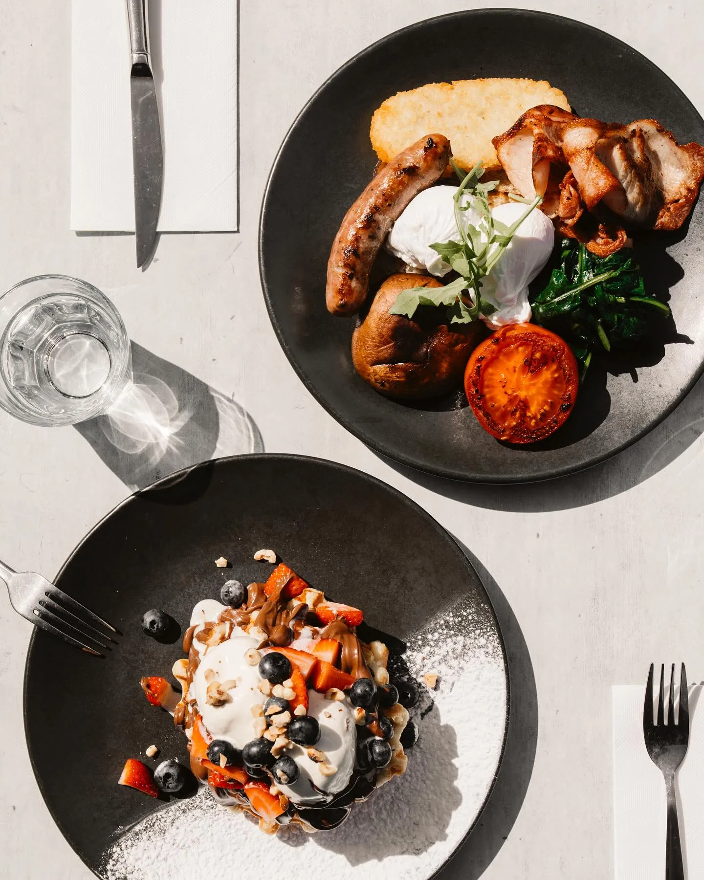 Overhead of a big breakfast and waffles with berries, cream and chocolate drizzle