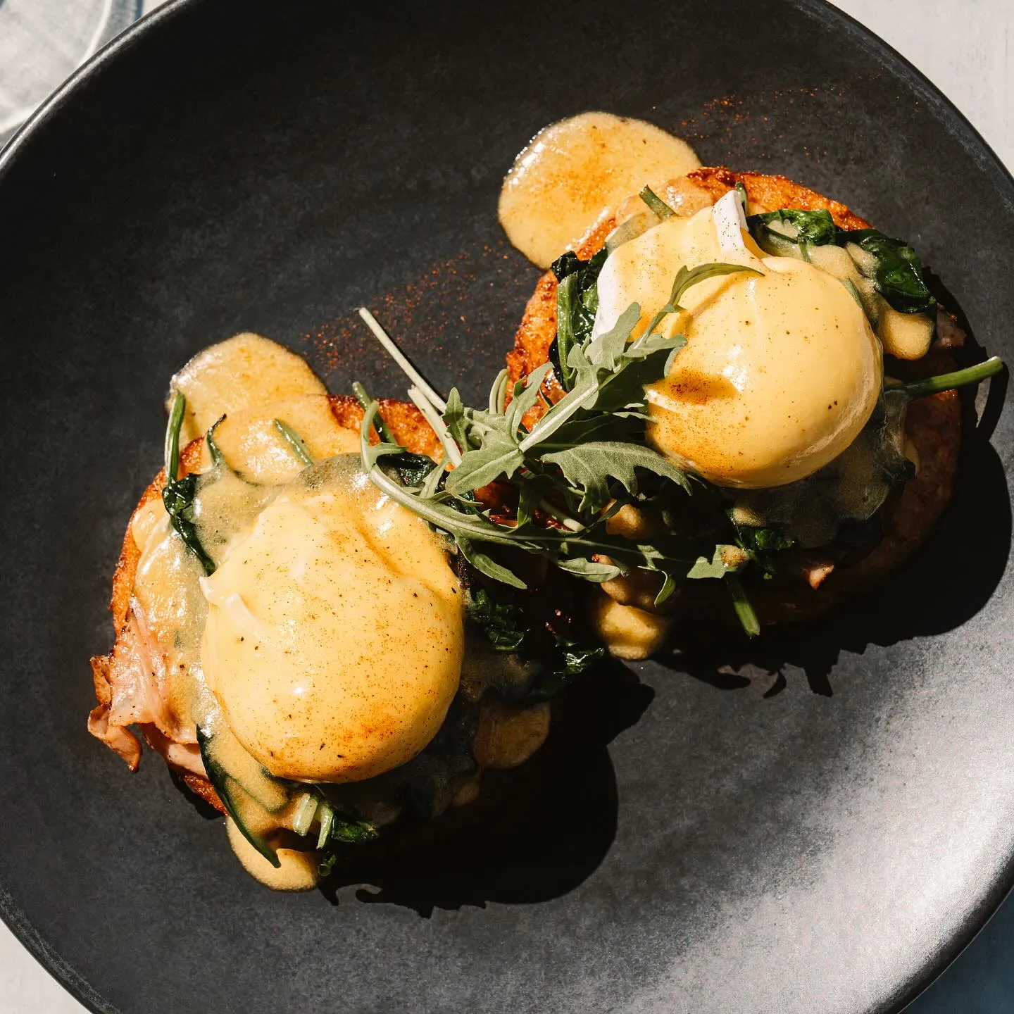 Close‑up of Eggs Benedict with hollandaise, spinach and rocket on potato rosti